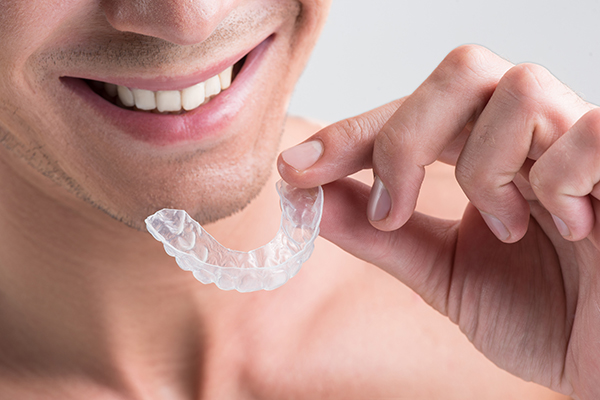 Cheerful young nude guy is holding plastic transparent brace